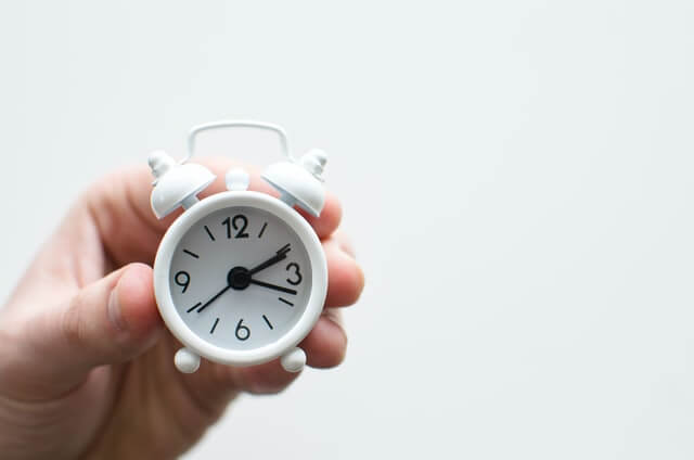 Close up photo of a hand holding a small alarm clock. The time reads 02:18:39. You are running out of time to qualify for Government Rebates for Windows!
