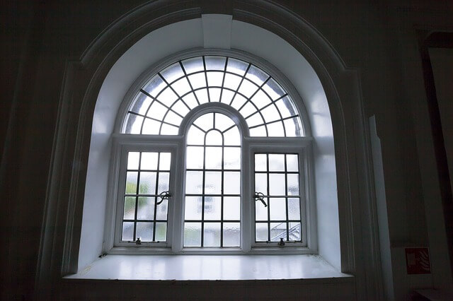 A grand half-round arched window adorned with decorative bars casts an imposing silhouette.