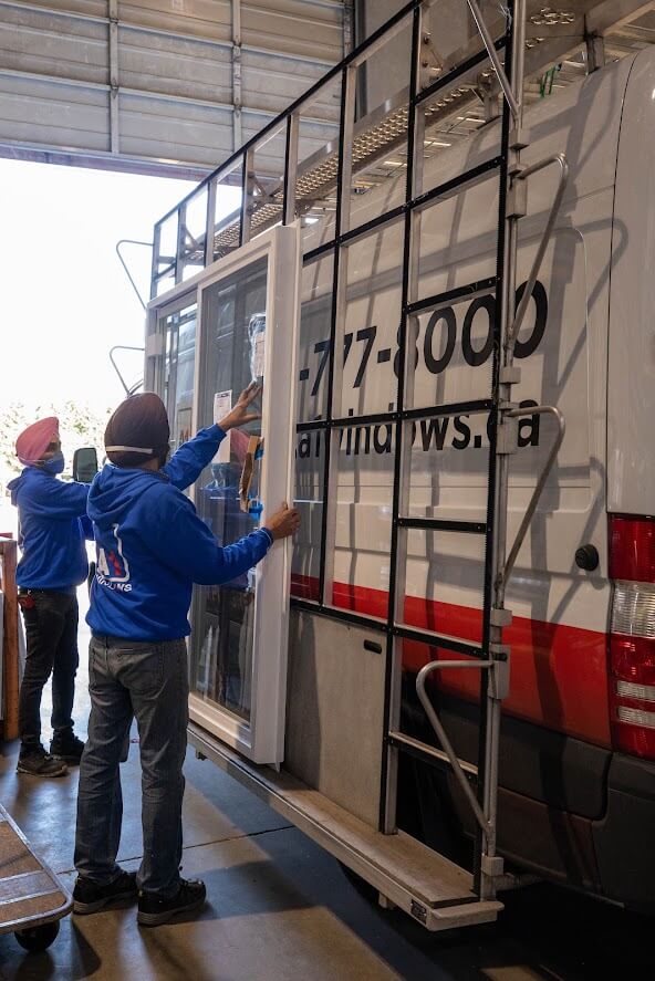 Two A-1 Windows Installers are loading windows onto the glazing rack of one of the branded vans. 