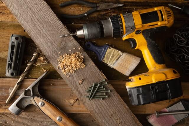 Miscellaneous tools are spread out over a wooden surface. These are common tools of window replacements.