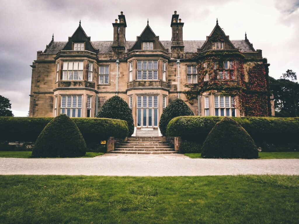 The garden view of a large stone mansion. The sightlines provided from the newly renovated windows show how window styles and pop out of the building.